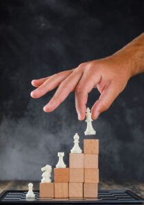 Business success concept with chessboard on wooden and foggy background side view. man placing figure on pyramid of blocks. Cloud Strategie